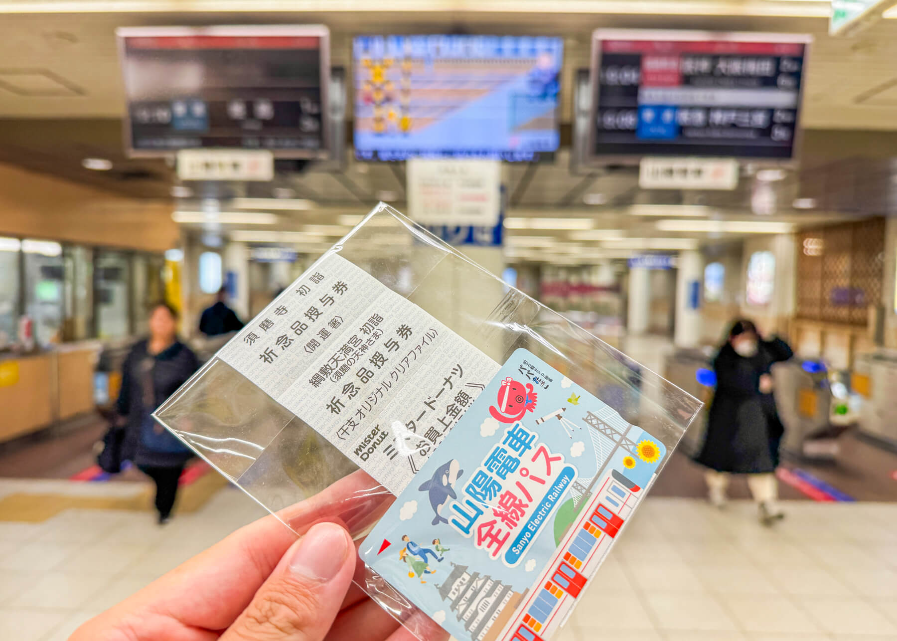 駅の改札前で、山陽電車全線パスを左手に持っている写真