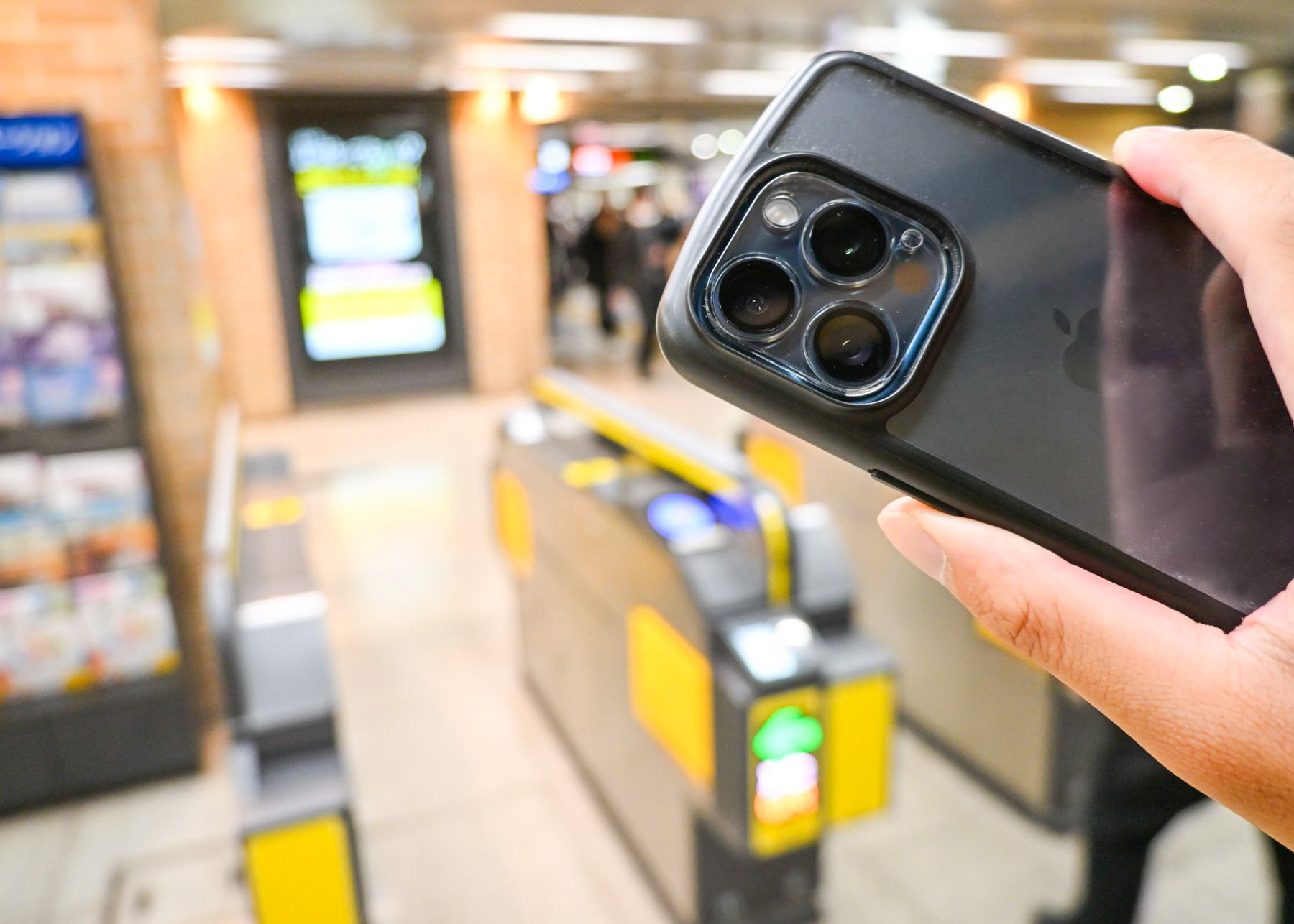 改札の前でスマートフォン右手に持ちをかざそうとしてる写真